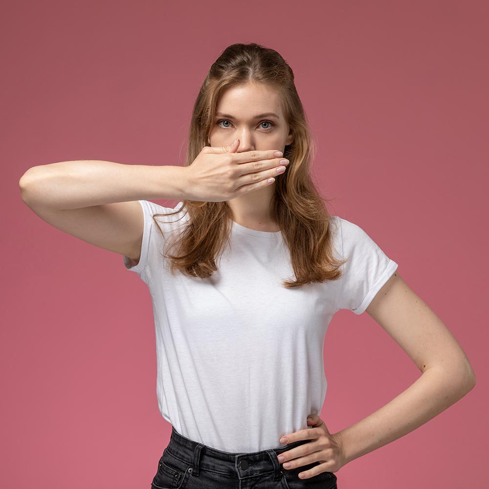 Eine Frau hält sich eine Hand vor ihren Mund, um Mundgeruch zu vermeiden