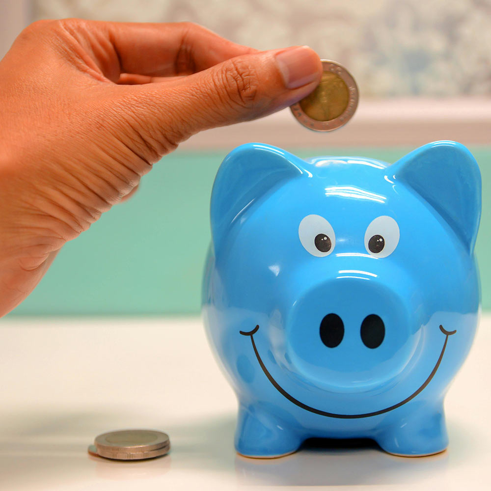 Ein Mann tut ein 2-Euro-Stück in ein Sparschwein